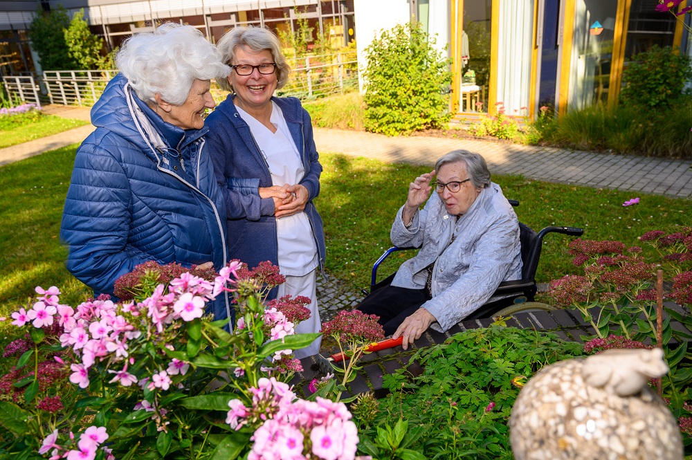 Eine Pflegerin mit zwei Bewohnerinnen an den Hochbeeten