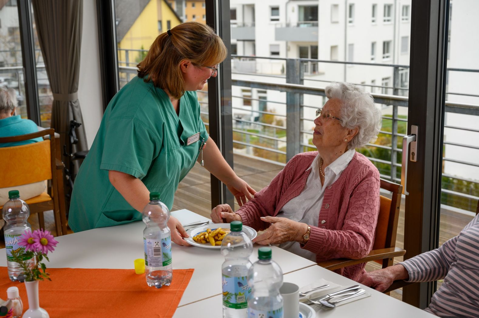 Eine Pflegerin serviert einer Bewohnerin das Essen