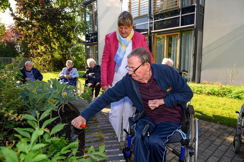 Ein Bewohner gärtnert am Hochbeet