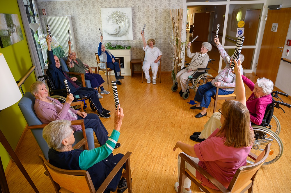 Bewohnerinnen machen Gymnastik mit einer Pflegerin