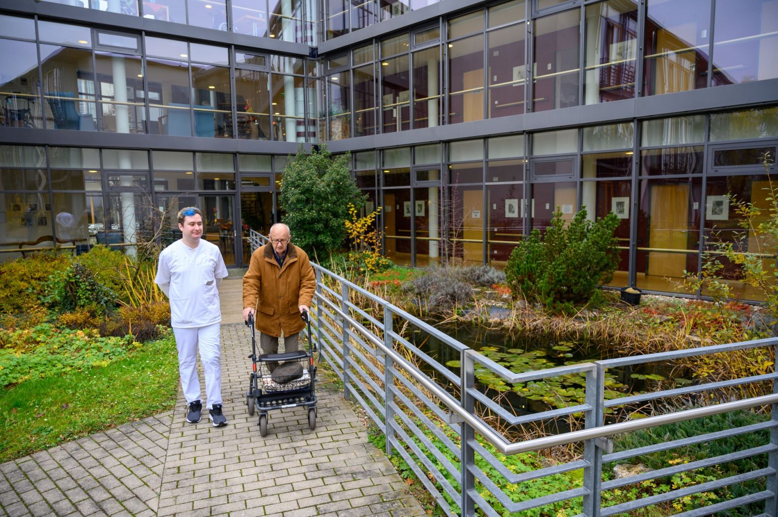 Ein Pfleger geht zusammen mit einem Bewohner draußen spazieren