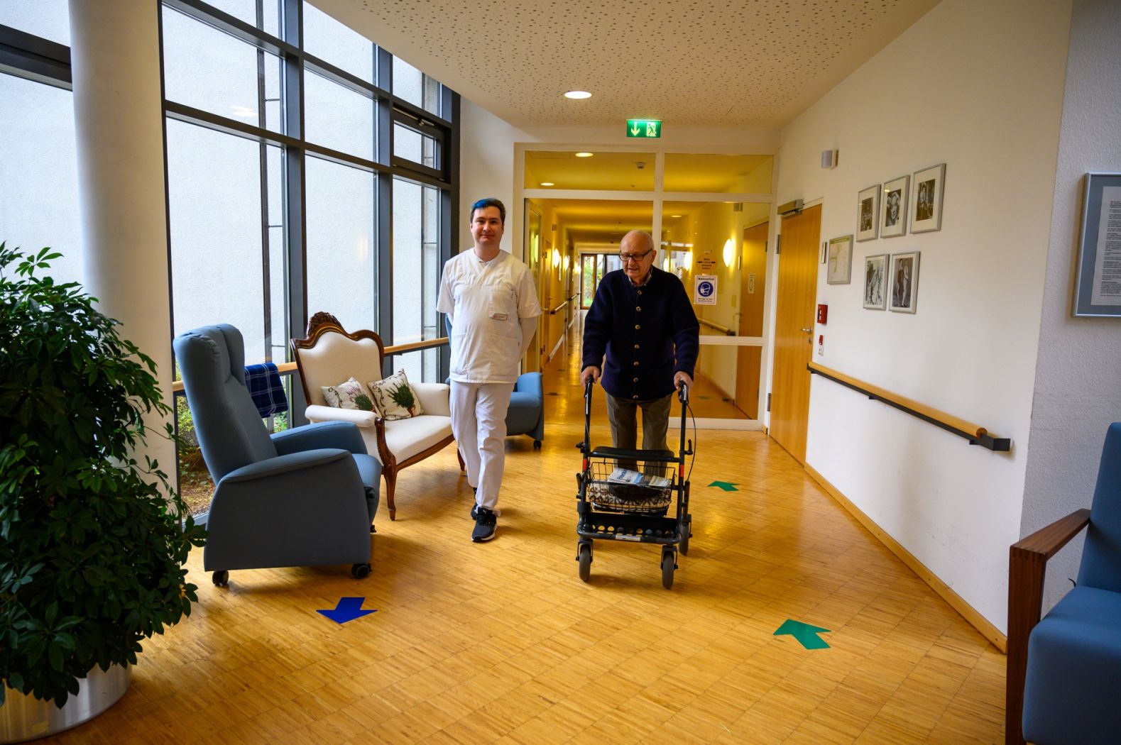 Ein Pfleger geht zusammen mit einem Bewohner durch das Pflegeheim