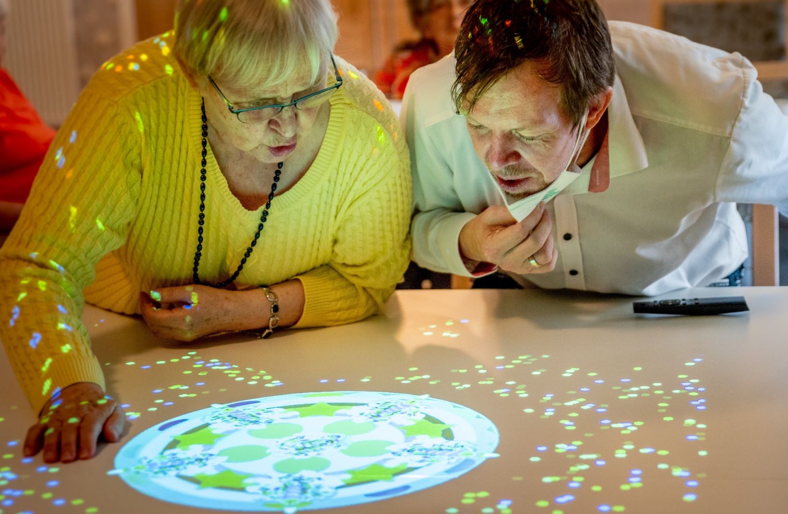 Eine Pflegeheim-Bewohnerin testet zusammen mit einem Pfleger die Tovertafel aus