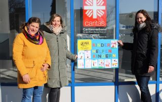 Symbolische Spendenübergabe vor dem Eingang zum Caritasverband