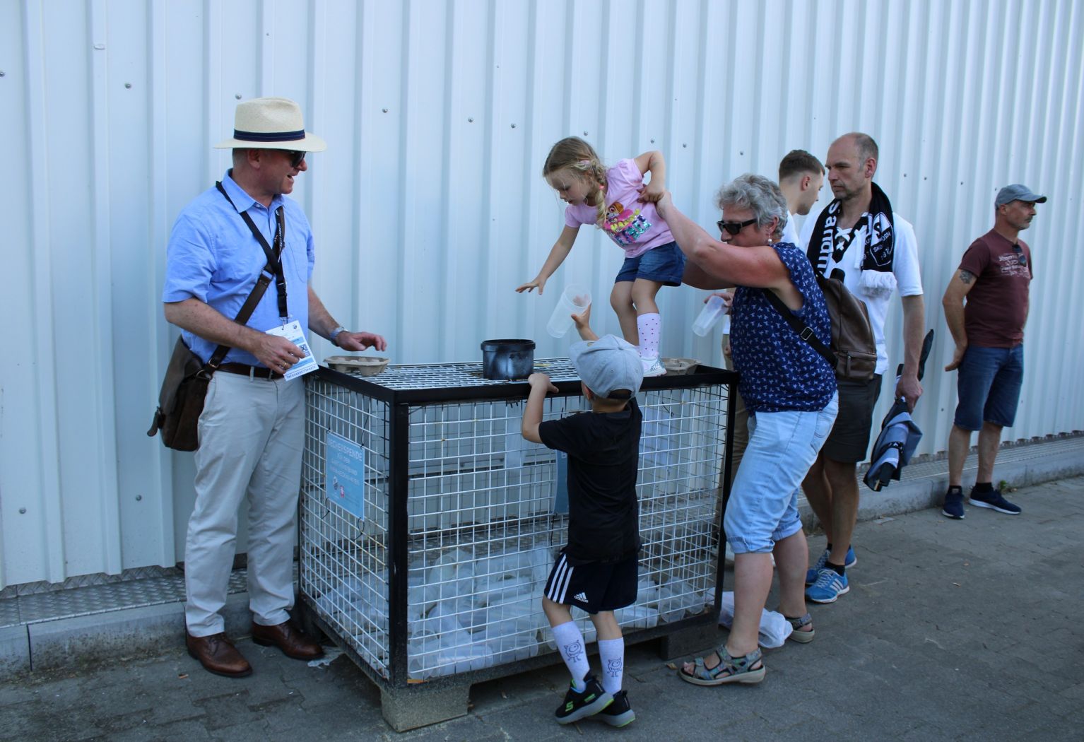 Kinder werfen ihre Becher als Spende in die große Gitterboxen