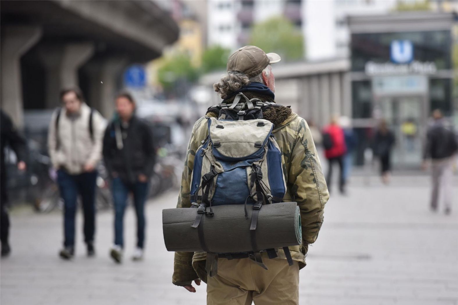 Obdachloser Mann mit Rucksack von hinten