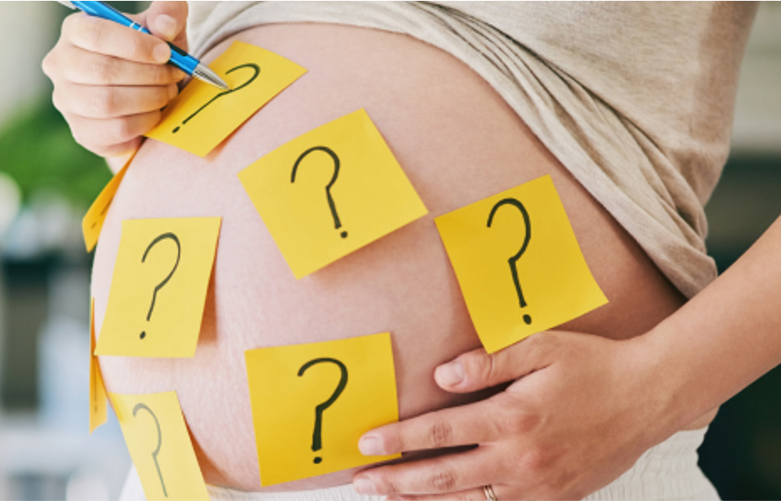 Ein schwangerer Bauch mit vielen Fragezeichen-Postits beklebt